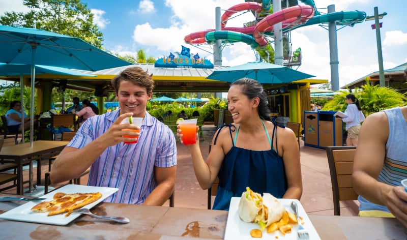 Man and woman enjoying food in front of a waterslide