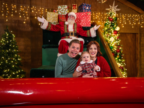 Family in a red sled with Santa in the background