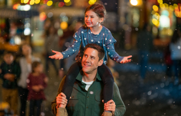 Young girl on the shoulders of her Dad at SeaWorld Orlando Christmas Celebration.