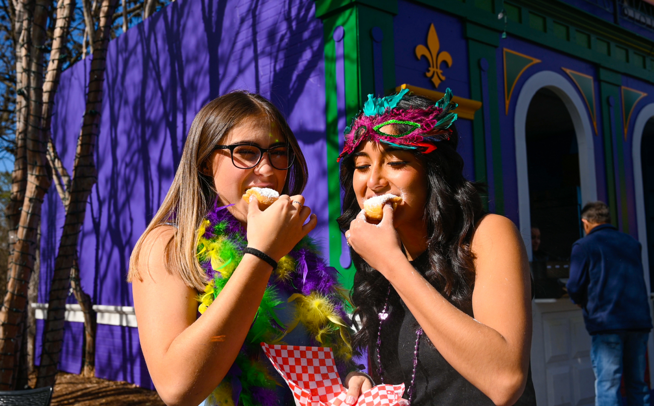 Two people eating beignets