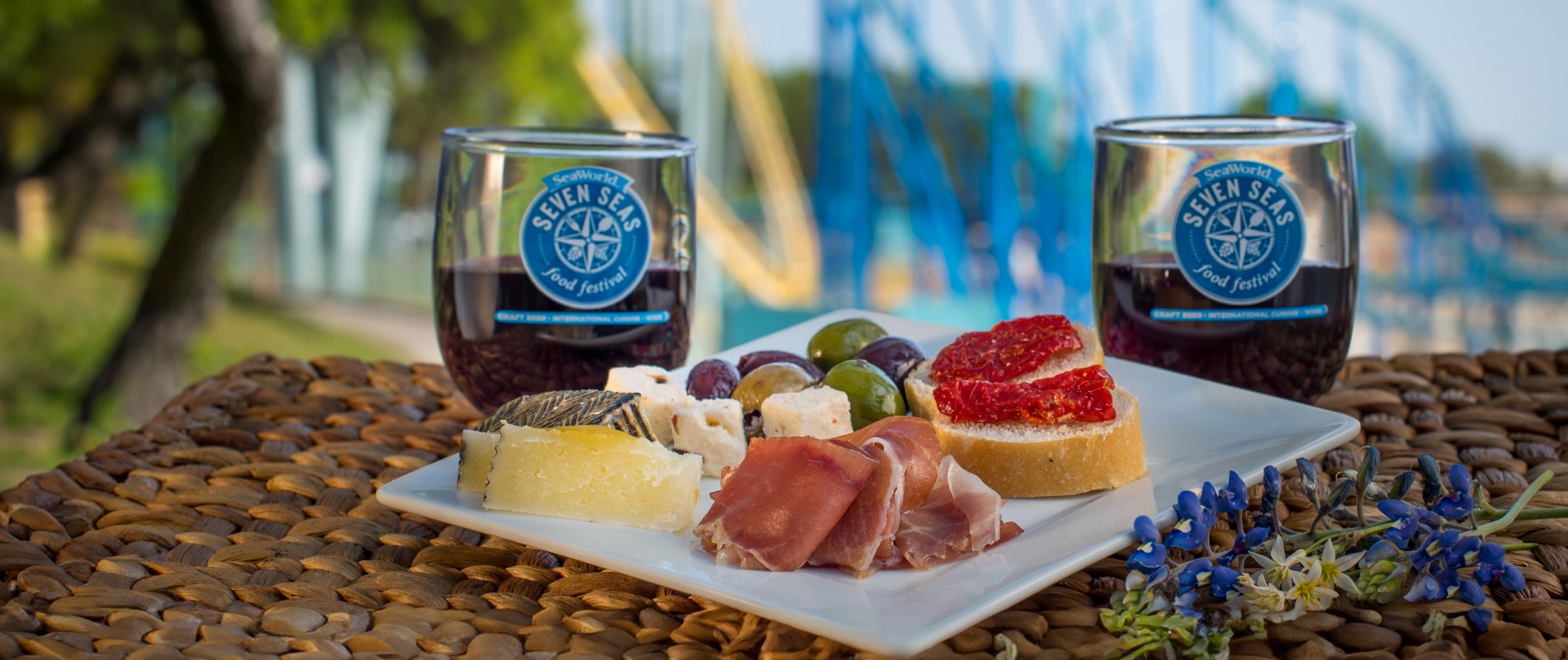 A plate of food and two wine glasses from the Seven Seas Food Festival at SeaWorld San Antonio.