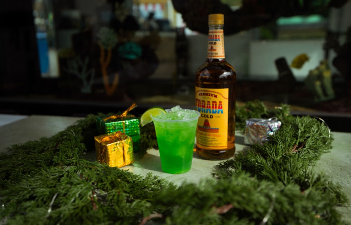 Green cocktail with a bottle of liquor surrounded by moss