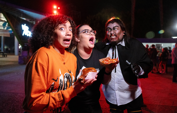 Two scared people holding food next to a halloween scare actor