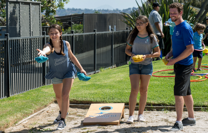 Three people playing cornhole