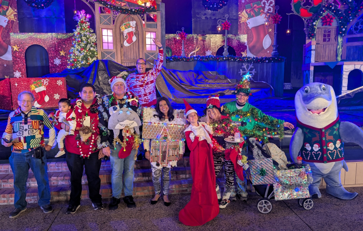 A group wearing ugly Christmas sweaters next to a shark mascot at SeaWorld San Diego 