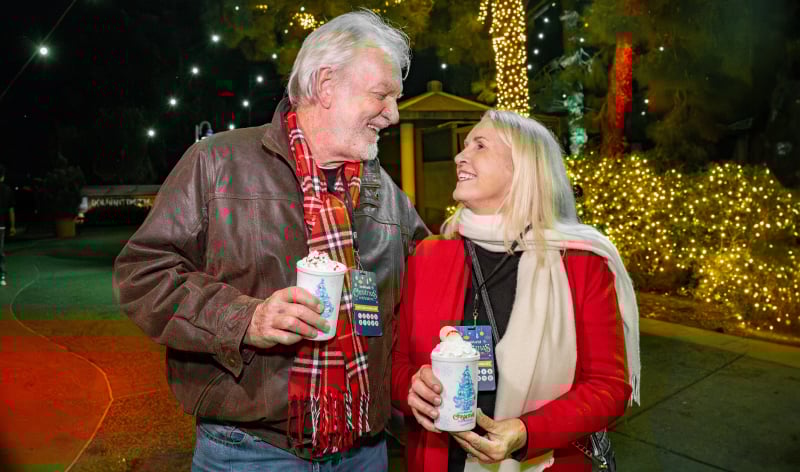A man and woman with SeaWorld San Diego hot chocolates and food and beverage sampler lanyards