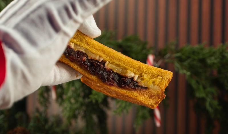 A white gloved hand holding a sandwich