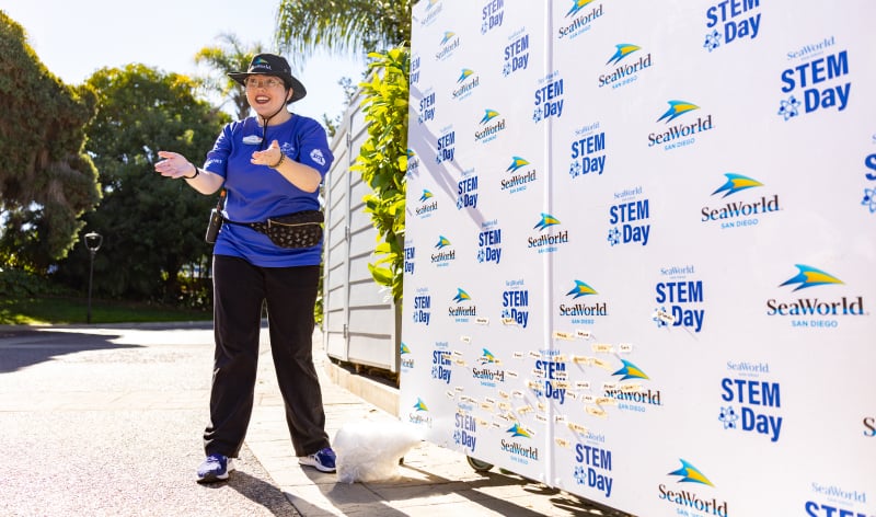 SeaWorld Ambassador in front of a STEM Day step and repeat banner
