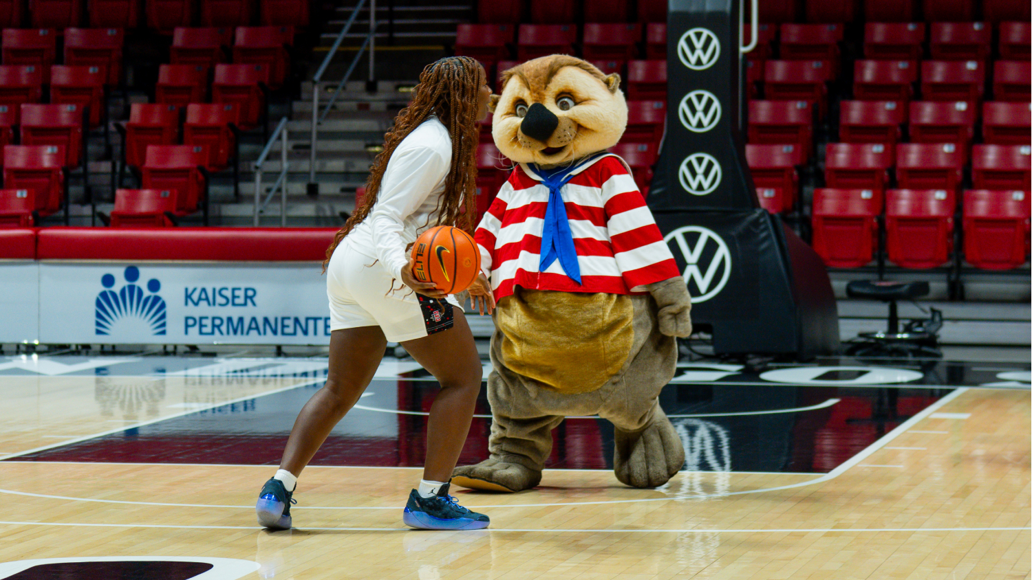 Basketball player with Sea Otter costumed mascot