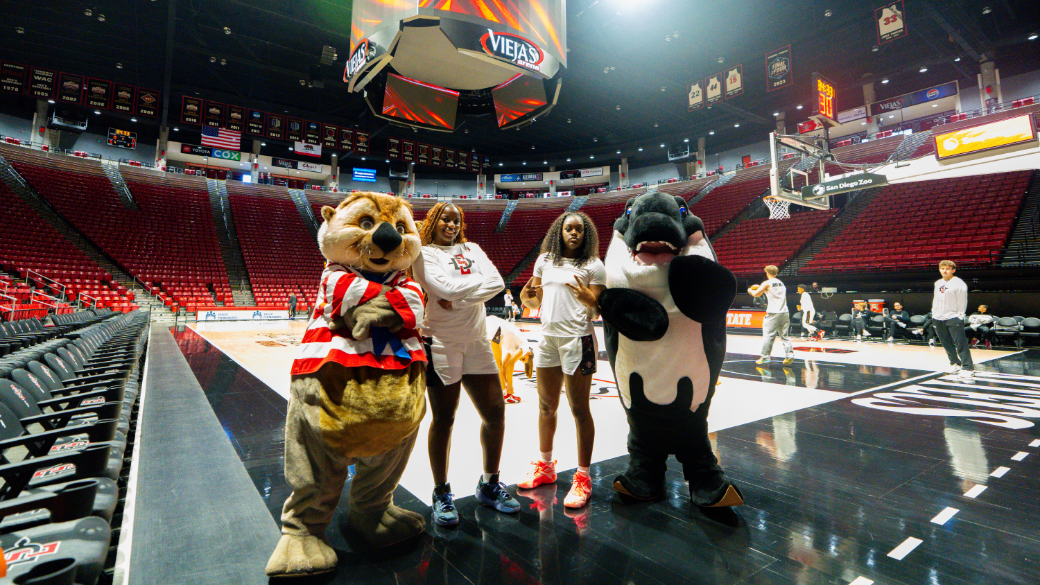 Two basketball players with two costumed mascots