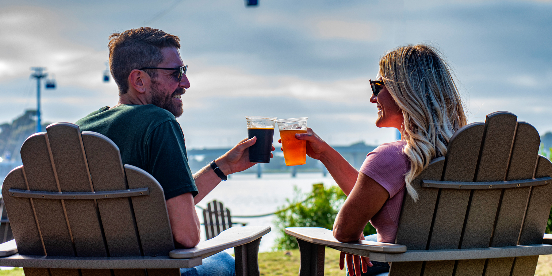Two people on Adirondack chairs with beers