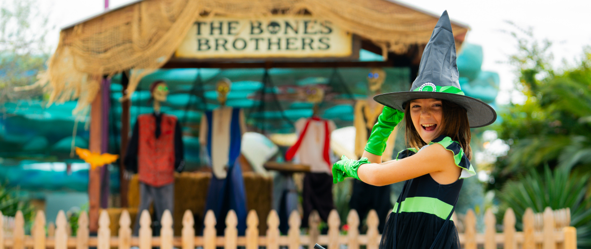 Child dressed as a witch with The Bones Brother show behind her