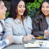 Four adults eating food at a table