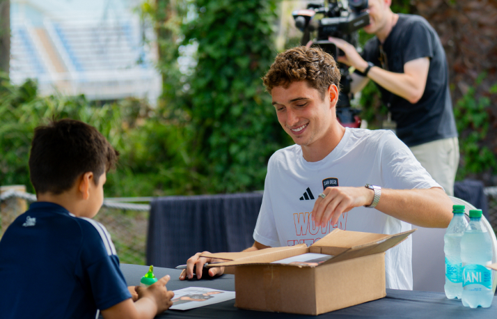 Soccer player signing autograph in front of a child