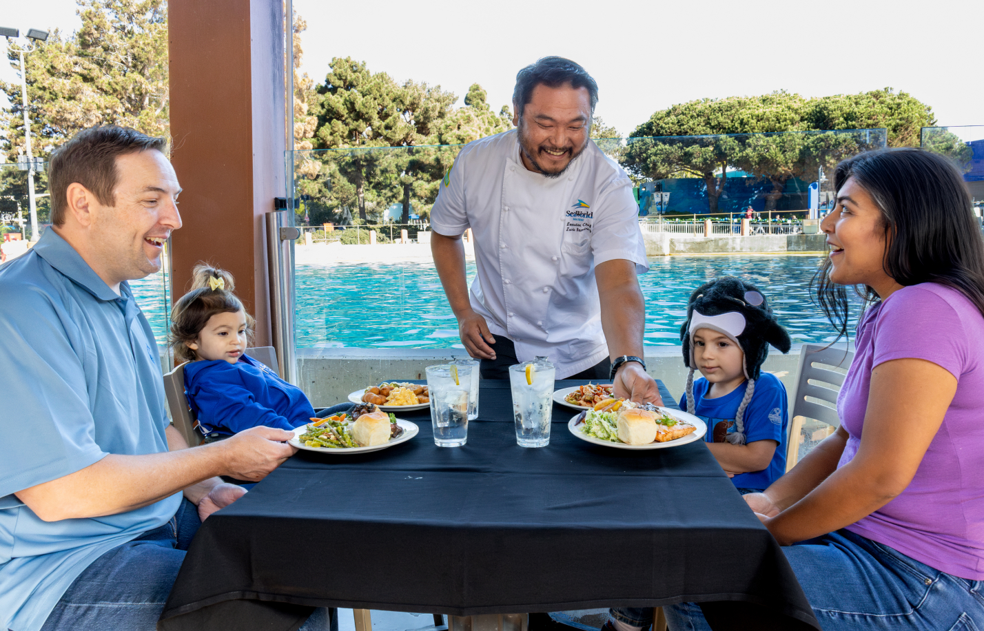 Family of four at a restaurant on the water with a server