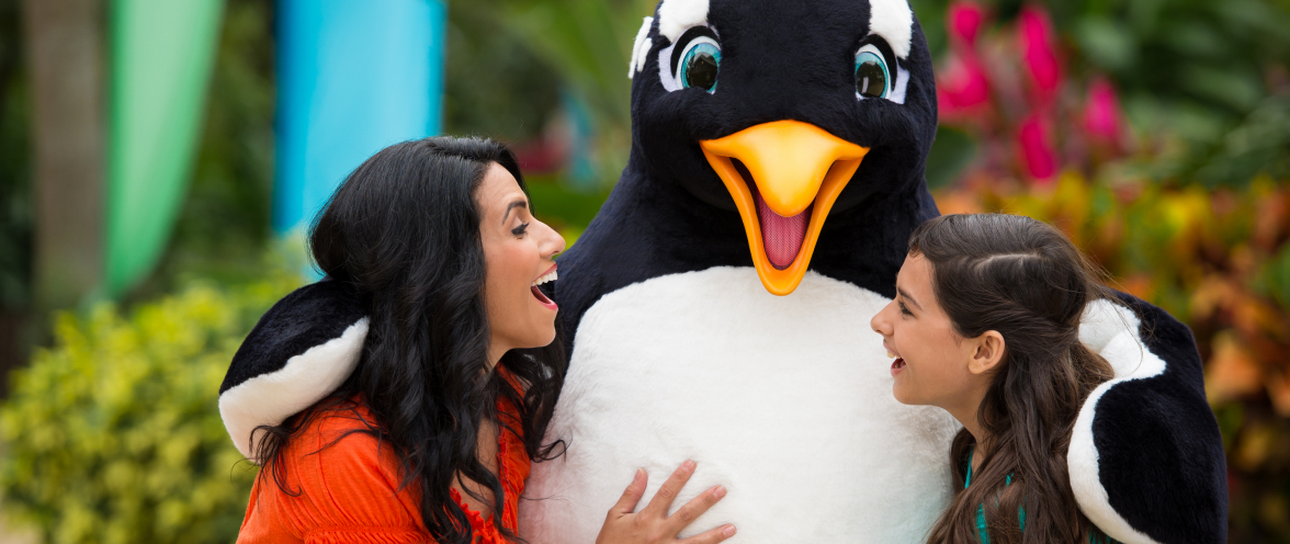 Two people with penguin mascot