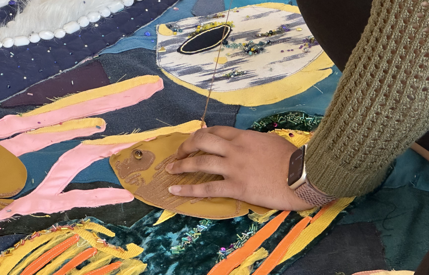 a person creating a fabric fish art piece