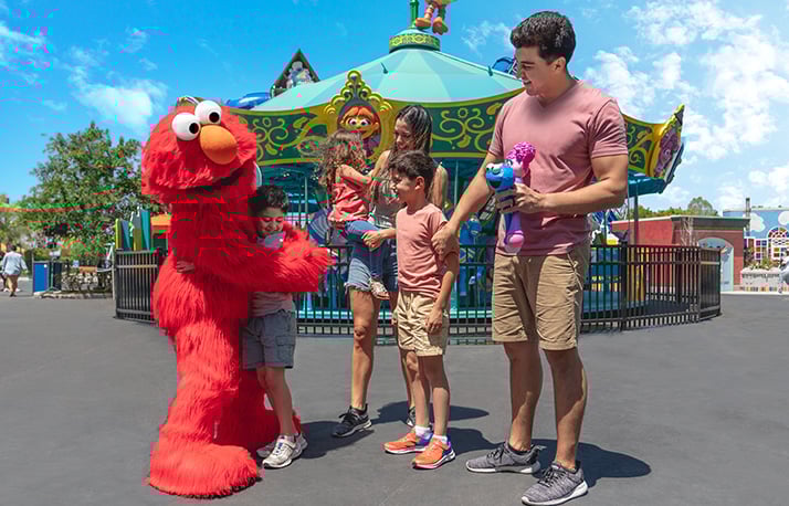 Family of four in front of a carousel with Elmo